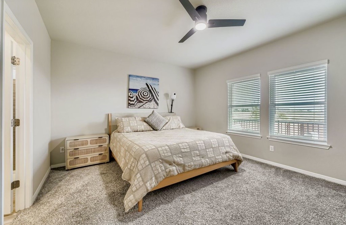 A bright bedroom at HIS House with a ceiling fan and two windows