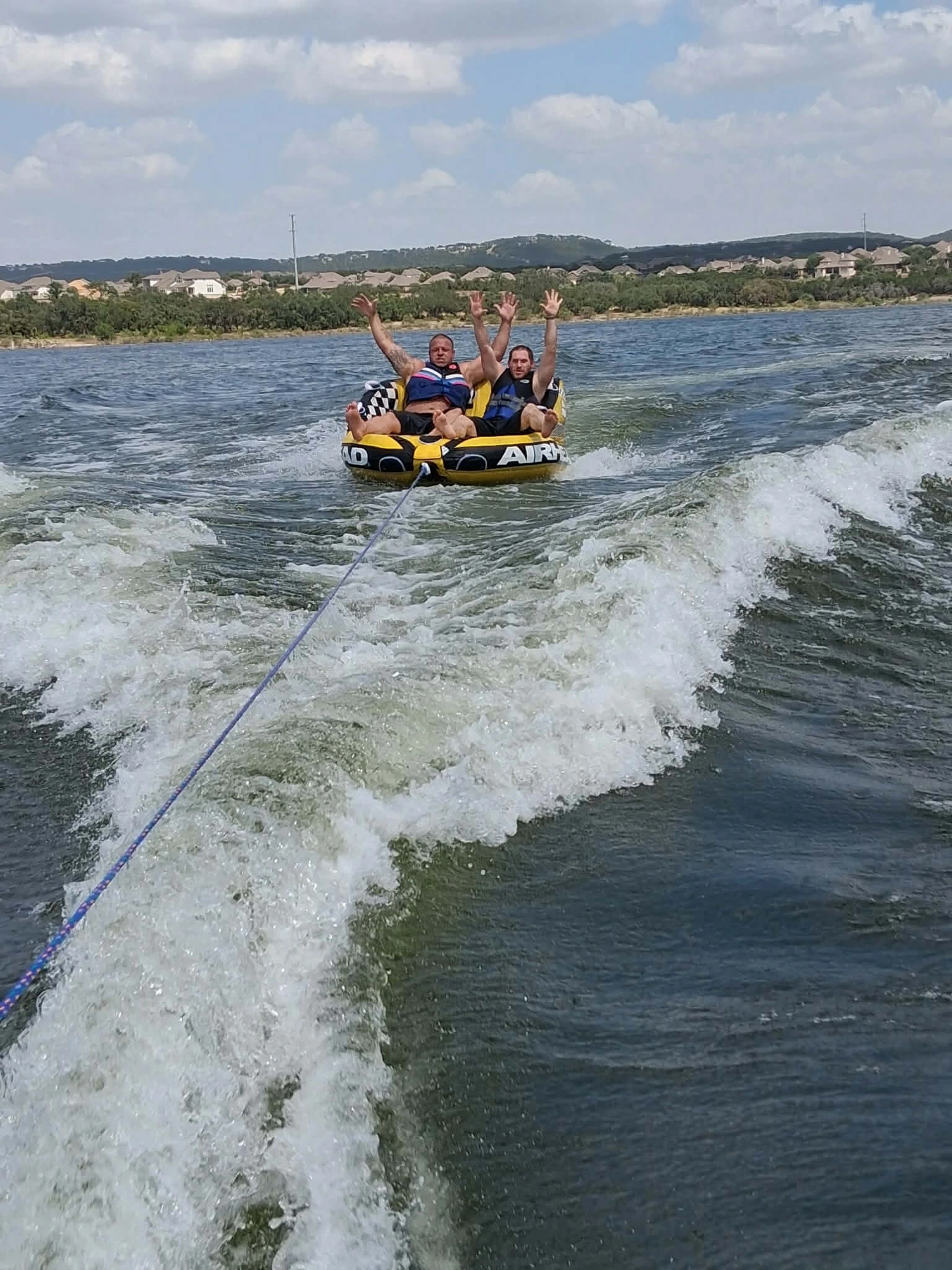 HIS House residents tubing on a lake day, hands in the air